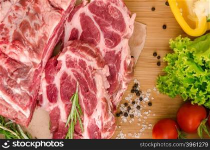 Raw meat with vegetables and spices on wooden background