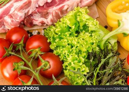 Raw meat with vegetables and spices on wooden background