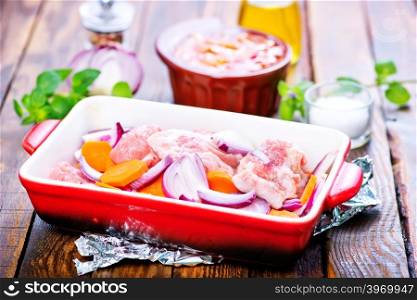 raw meat with vegetables in the bowl and on a table