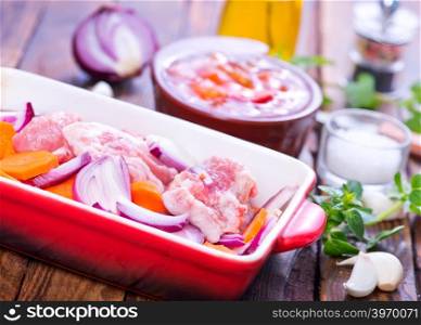 raw meat with vegetables in the bowl and on a table