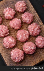 Raw meatballs of minced meat beef, pork or chicken with salt, spices and herbs on a dark concrete background