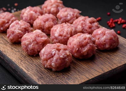 Raw meatballs of minced meat beef, pork or chicken with salt, spices and herbs on a dark concrete background