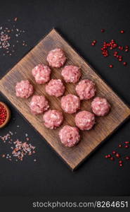 Raw meatballs of minced meat beef, pork or chicken with salt, spices and herbs on a dark concrete background