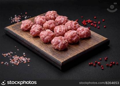 Raw meatballs of minced meat beef, pork or chicken with salt, spices and herbs on a dark concrete background