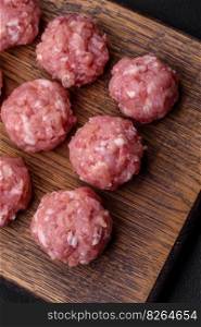 Raw meatballs of minced meat beef, pork or chicken with salt, spices and herbs on a dark concrete background