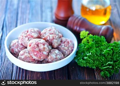 raw meatballs on plate and on a table