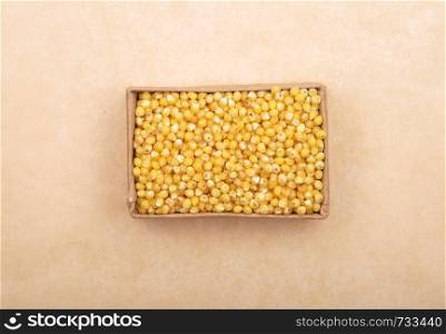 Raw millet in carton and on brown background