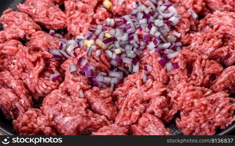 Raw mince beef, ground meat. Black background. Top view. Copy space. Fresh raw mince with spices and herbs on a dark concrete background