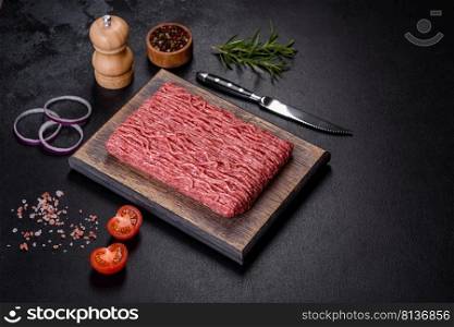 Raw mince beef, ground meat. Black background. Top view. Copy space. Fresh raw mince with spices and herbs on a dark concrete background