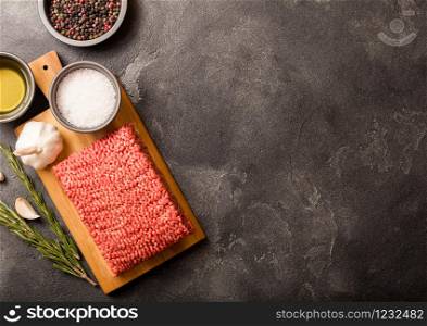Raw minced homemade beef meat with spices and herbs. Top view. On top of chopping board and kitchen table background. With pepper salt and garlic.