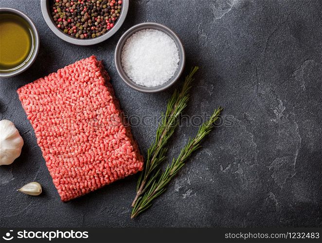 Raw minced homemade beef meat with spices and herbs. Top view. On top of kitchen table background. With pepper salt and garlic.