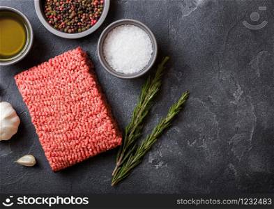 Raw minced homemade beef meat with spices and herbs. Top view. On top of kitchen table background. With pepper salt and garlic.
