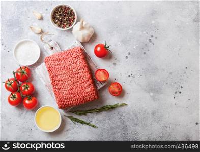 Raw minced homemade beef meat with spices and herbs. Top view. On top of chopping board and marble kitchen table background. With pepper salt and garlic.