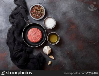 Raw minced homemade grill beef burger in frying pan. Top view and space for text. With pepper salt and garlic with black cloth.