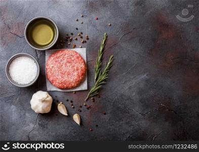 Raw minced homemade grill beef burger with spices and herbs. Top view and space for text. Pepper, salt and oil on kitchen table background.