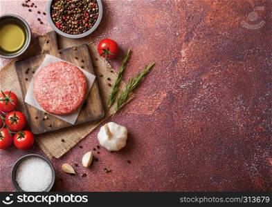 Raw minced homemade grill beef burger with spices and herbs. Top view and space for text. On top of chopping board and rusty kitchen table background. With pepper salt and garlic.