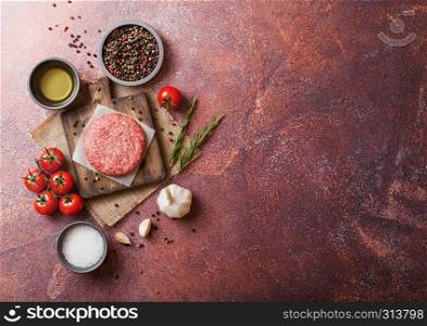Raw minced homemade grill beef burger with spices and herbs. Top view and space for text. On top of chopping board and rusty kitchen table background. With pepper salt and garlic.