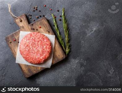 Raw minced homemade grill beef burger with spices and herbs. Top view and space for text. On top of chopping board and kitchen table background.