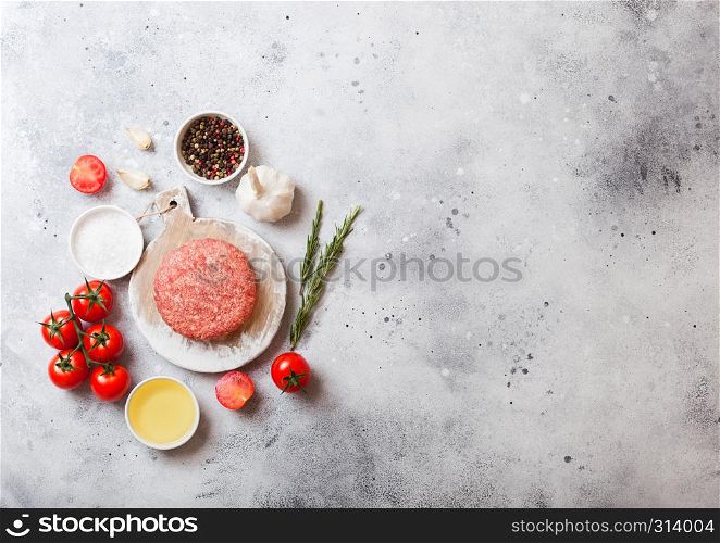 Raw minced homemade grill beef burger with spices and herbs. Top view. On top of white chopping board and kitchen table background. With pepper salt and garlic.