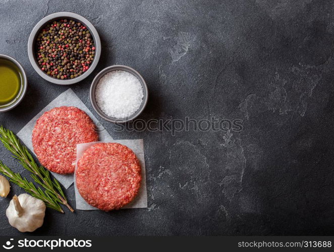 Raw minced homemade grill beef burgers with spices and herbs. Top view and space for text. Pepper, salt and oil on kitchen table background.