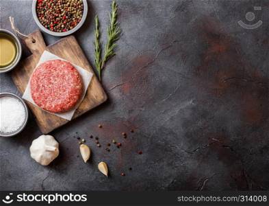 Raw minced homemade grill beef burgers with spices and herbs. Top view and space for text. On top of chopping board and kitchen table background. With pepper salt and oil.