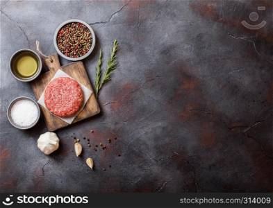 Raw minced homemade grill beef burgers with spices and herbs. Top view and space for text. On top of chopping board and kitchen table background. With pepper salt and oil.