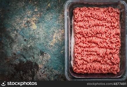 Raw minced meat in plastic box on rustic background, top view, place for text