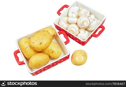 Raw mushrooms and potatoes in red trays, isolated on white
