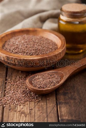 Raw natural organic linseed flax-seed in wooden bowl with spoon and oil on wood background. Healthy omega 3 product.