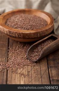 Raw natural organic linseed flax-seed in wooden bowl with spoon on wood background. Healthy omega 3 product.