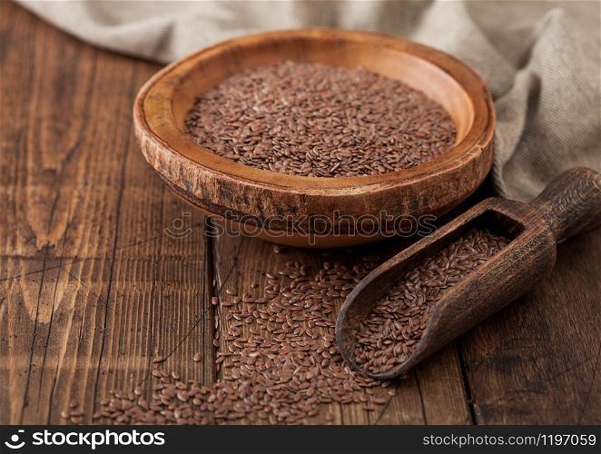 Raw natural organic linseed flax-seed in wooden bowl with spoon on wood background. Healthy omega 3 product.