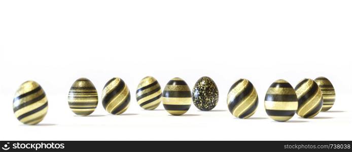 Raw of black and gold Easter eggs, balanced on its blunt end on grey background. Easter decoration seamless banner concept