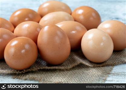Raw organic brown farm eggs on burlap cloth background