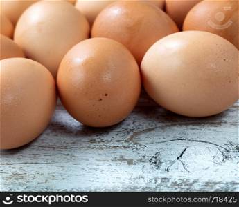 Raw organic brown farm eggs on white rustic wooded background