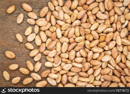 raw organic cacao beans on a weathered wood background