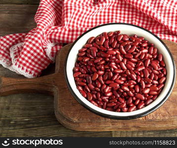 raw oval red beans in a plate on a wooden table. Organic meal. Vegetarian healthy natural food.