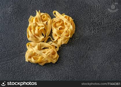 Raw pappardelle - flat Italian pasta noodles on wooden background