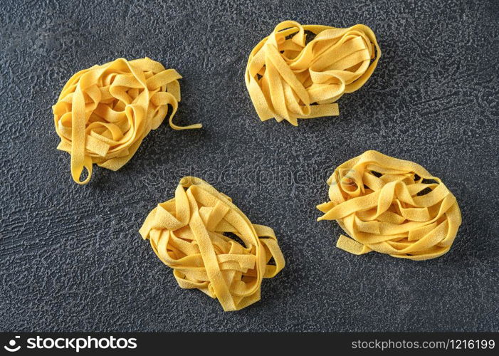 Raw pappardelle - flat Italian pasta noodles on wooden background