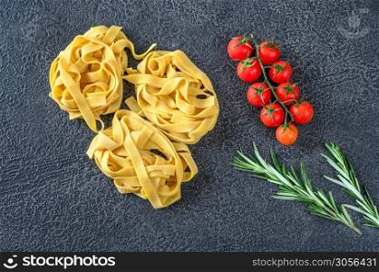 Raw pappardelle - flat Italian pasta noodles with cherry tomatoes and fresh rosemary