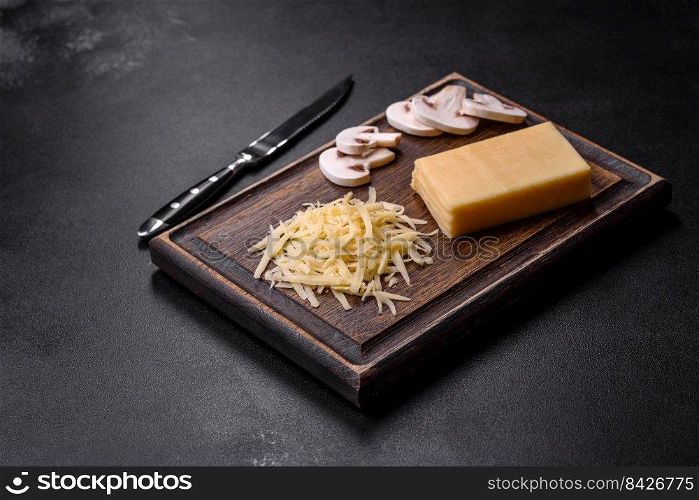 Raw pasta, mushrooms, onions, mince, spices and herbs to make a delicious paste with tomato sauce against a dark concrete background. Raw pasta, mushrooms, onions, mince, spices and herbs to make a delicious paste