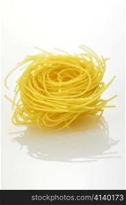 Raw pasta nest on a white background