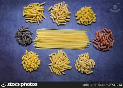 Raw pasta various kinds of uncooked pasta macaroni spaghetti and noodles on wooden, Italian food culinary concept, Collection of different raw pasta on cooking table for cooking food - top view