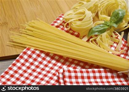 Raw pasta with basil leaf on kitchen towel