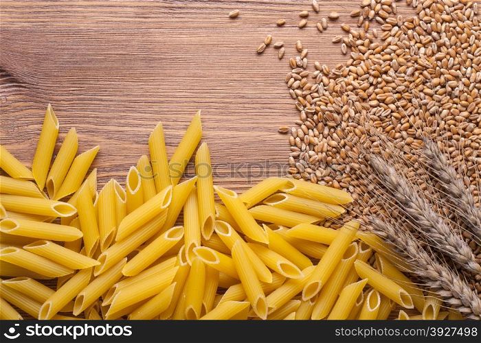raw pasta with ears and flour on wood background