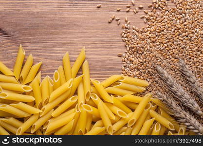 raw pasta with ears and flour on wood background