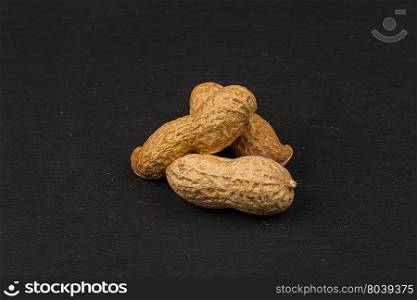 Raw peanuts shells over dark stone background
