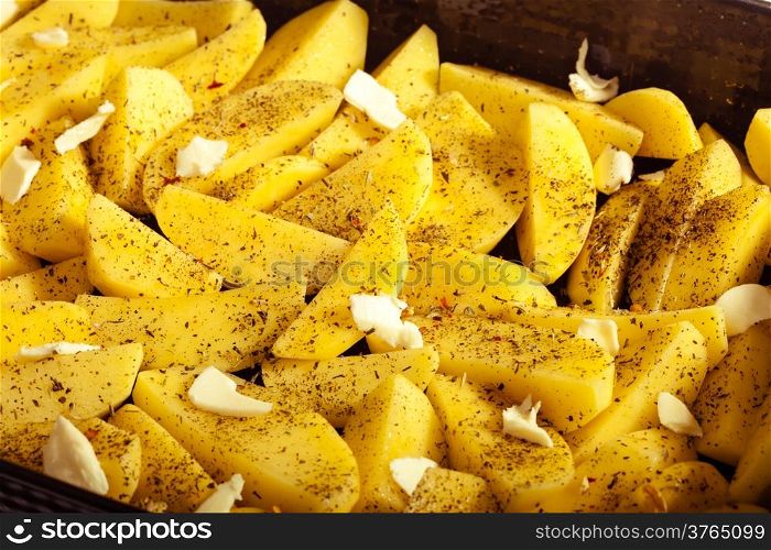 Raw peeled potatoes with spices and butter slices ready to be roasted as food background