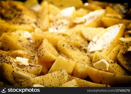 Raw peeled potatoes with spices, butter slices ready to be roasted as background