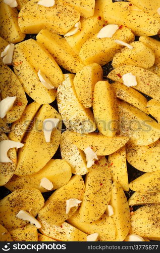 Raw peeled potatoes with spices, butter slices ready to be roasted as background