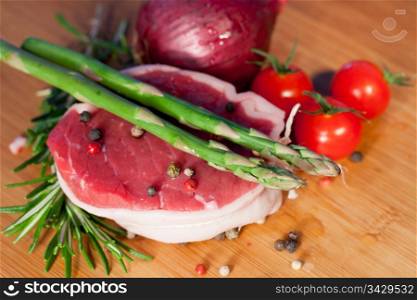 Raw piece of beef with rosemary and asparagus